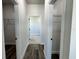 Hallway with open closet spaces, wood floors, and white walls, leading to a bright room at 15750 Sw 40Th Ter Sw 40Th Ter, Ocala, FL 34473