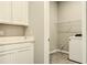 Bright laundry room with gray tile flooring, overhead wire shelving, and white cabinetry with light countertop at 16271 Silver Grove Blvd, Winter Garden, FL 34787
