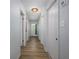 Hallway with white doors, light-colored walls, and wood-look flooring, leading to a bright entryway at 1635 Magnolia Ave, South Daytona, FL 32119