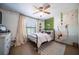 Charming bedroom with a metal frame bed, ceiling fan, window with curtains, and decorative plants at 1651 Big Oak Ln, Kissimmee, FL 34746