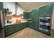 Modern kitchen with sleek green cabinets, stainless steel appliances, and custom shelving at 1651 Big Oak Ln, Kissimmee, FL 34746