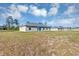 Back view of home with sliding glass door and windows; large grassy yard with trees at 16771 Sw 21St Terrace Rd, Ocala, FL 34473