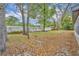 View of the backyard with grass, leaf cover, mature trees and white perimeter fence at 217 E Hillcrest St, Altamonte Springs, FL 32701
