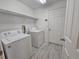 Bright laundry room with washer, dryer, shelving, and white tile floors at 224 Lake Charles Dr, Davenport, FL 33837