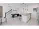 Open living space with a modern kitchen, tile flooring, air hockey table, and staircase at 2400 Reading Trl, Kissimmee, FL 34746