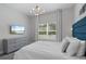 Bright main bedroom featuring a large window, stylish lighting, and a comfortable bed with modern decor and TV at 2400 Reading Trl, Kissimmee, FL 34746