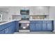 Well-lit kitchen showcasing stainless steel appliances, and white and blue cabinets at 358 Prevo Dr, Apopka, FL 32712
