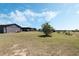 View of barn and covered parking on expansive lot with green grass under a blue sky at 4400 Walker Lake Rd, Bartow, FL 33830