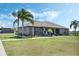 Gray home featuring a well-manicured lawn, inviting front porch with rocking chairs, and mature palm trees at 4400 Walker Lake Rd, Bartow, FL 33830
