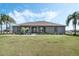 Charming gray home featuring a well-manicured lawn, inviting front porch with rocking chairs, and mature palm trees at 4400 Walker Lake Rd, Bartow, FL 33830