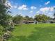 Aerial view of a well-manicured backyard with lush green grass, mature trees, and a screen enclosed patio at 51 Park Ln, Debary, FL 32713