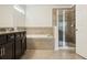 This bathroom features a tiled bathtub, walk-in shower, dark cabinetry and granite countertops at 611 Marsh Reed Dr, Winter Garden, FL 34787