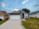 Charming single-story home features a two-car garage, gray stucco exterior, and arched front entry at 721 Rollins Dr, Davenport, FL 33837