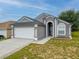 Inviting gray home featuring a two-car garage, fresh lawn, and a covered entryway at 721 Rollins Dr, Davenport, FL 33837