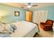 Comfortable bedroom featuring a metal bedframe, closet, and a relaxing orange recliner at 760 Eastridge Dr, Orange City, FL 32763