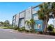 Modern three-story building with a blue and grey exterior surrounded by small palm trees and manicured landscaping at 7770 Sandy Ridge Dr # 207, Reunion, FL 34747