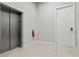 Well-lit hallway featuring tile floors, an elevator, apartment doors, and safety equipment for secure living at 7770 Sandy Ridge Dr # 207, Reunion, FL 34747