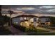 Exterior view of a well-lit two-story home with a tiled roof and lush landscaping at twilight at 8125 Via Rosa, Orlando, FL 32836