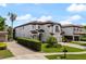Elegant two-story home with a tiled roof, manicured lawn, and brick driveway, exuding curb appeal at 8125 Via Rosa, Orlando, FL 32836