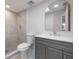 Bright bathroom featuring gray tiled walk-in shower, modern vanity, and arched mirror at 1148 Martin L King Dr, Orlando, FL 32805