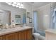 Bright bathroom with wooden vanity, large mirror, and a shower with a blue floral curtain at 13234 Moonflower Ct, Clermont, FL 34711