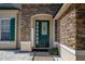 Close-up of front door with green paint, decorative glass, and stacked stone surround at 13247 Hatherton Cir, Orlando, FL 32832