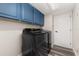 Well-equipped laundry room with blue cabinetry and modern black washer and dryer units at 13247 Hatherton Cir, Orlando, FL 32832