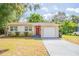 Charming single-story home featuring a red door, front yard, and attached one car garage at 1411 N Powers Dr, Orlando, FL 32818