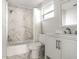 All white bathroom features tile floor, marble accent wall, tub, and single sink vanity at 1506 37Th St, Orlando, FL 32839