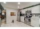 Well-lit kitchen featuring stainless steel appliances, white cabinetry, and open access to the living room at 1506 37Th St, Orlando, FL 32839