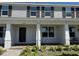 Front exterior view of a two-story townhome, showcasing a covered porch with white columns at 15098 Windflower Aly, Winter Garden, FL 34787