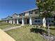 View of a two-story townhome exterior with a covered porch, landscaped front yard, and brick walkway at 15098 Windflower Aly, Winter Garden, FL 34787