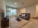 Cozy living room featuring a plush gray sofa, patterned rug, and a bright window with sheer curtains at 15098 Windflower Aly, Winter Garden, FL 34787