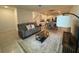 Living room with cozy gray sofa, patterned rug, and a view of the open-concept dining and kitchen area at 15098 Windflower Aly, Winter Garden, FL 34787
