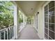 A spacious covered balcony with white columns and railing overlooks lush greenery at 1630 Common Way Rd # 303, Orlando, FL 32814