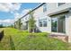 The exterior of the home showing the backyard with sliding glass doors and a young tree at 16447 Bird Of Paradise Ave, Clermont, FL 34714