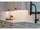 A modern farmhouse sink with a black faucet is surrounded by bright white countertops and stylish cabinets at 18026 Reynolds Pkwy, Orlando, FL 32833