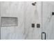 Close-up of the shower with elegant marble tile and a built-in niche for toiletries at 18026 Reynolds Pkwy, Orlando, FL 32833