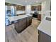 Modern kitchen with stainless steel appliances, an island with quartz countertops, and dark brown cabinetry at 2131 Nicollett Way, Leesburg, FL 34748