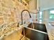 Close up of stainless sink with granite countertops and decorative tile backsplash in the kitchen at 241 Churchill Ct, Kissimmee, FL 34758