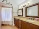Bathroom with granite counters, wood cabinets, framed mirrors and shower with white curtain at 2850 Tremont Dr, Eustis, FL 32726