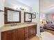 Granite countered double sink bathroom with framed mirrors, a shower, and a bedroom view at 2850 Tremont Dr, Eustis, FL 32726
