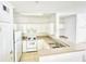 A well-lit kitchen with white cabinets and appliances with an adjacent bar that looks into the living room at 315 Grand Magnolia Ave # 112, Celebration, FL 34747