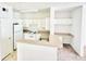 A well-lit kitchen with white cabinets and appliances with an adjacent bar that looks into the living room at 315 Grand Magnolia Ave # 112, Celebration, FL 34747