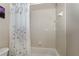 Neutral toned bathroom area with tiled walls, bathtub, and shower curtain with decorative flower pattern at 36300 Grand Island Oaks Cir, Grand Island, FL 32735