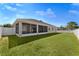 Rear view of home with screened-in patio, fenced yard, and well-maintained lawn at 36300 Grand Island Oaks Cir, Grand Island, FL 32735