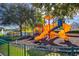 Colorful playground with slides and climbing structures, set against a backdrop of lush greenery and a lake at 4011 Venetian Bay Dr # 103, Kissimmee, FL 34741