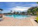 Community pool with lounge chairs, palm trees, and residential buildings under a sunny sky at 4011 Venetian Bay Dr # 103, Kissimmee, FL 34741