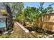 View of the backyard walking path between the fence and screened-in lanai with plenty of foliage and greenery at 4371 Vestawood Ct, Sanford, FL 32773