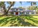 Charming two-story home with a lush green lawn and mature trees, plus solar panels, and a red front door at 5297 Mill Stream Dr, St Cloud, FL 34771